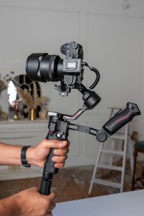 A person holding a camera with a tripod attached