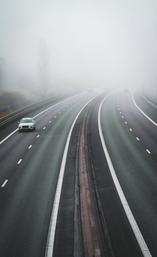 A highway with cars driving on it in the fog