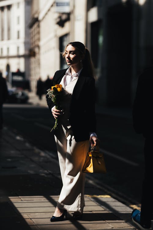 A woman walking down the street with a yellow flower