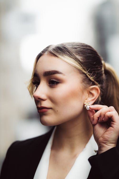 A woman in a suit and tie is holding her ear