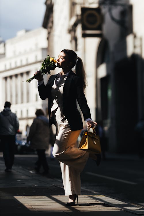 A woman in a suit holding a yellow flower
