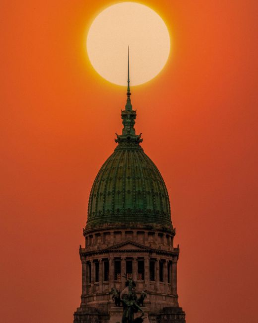 Dramatic silhouette of Buenos Aires Congreso building against a vivid sunset.