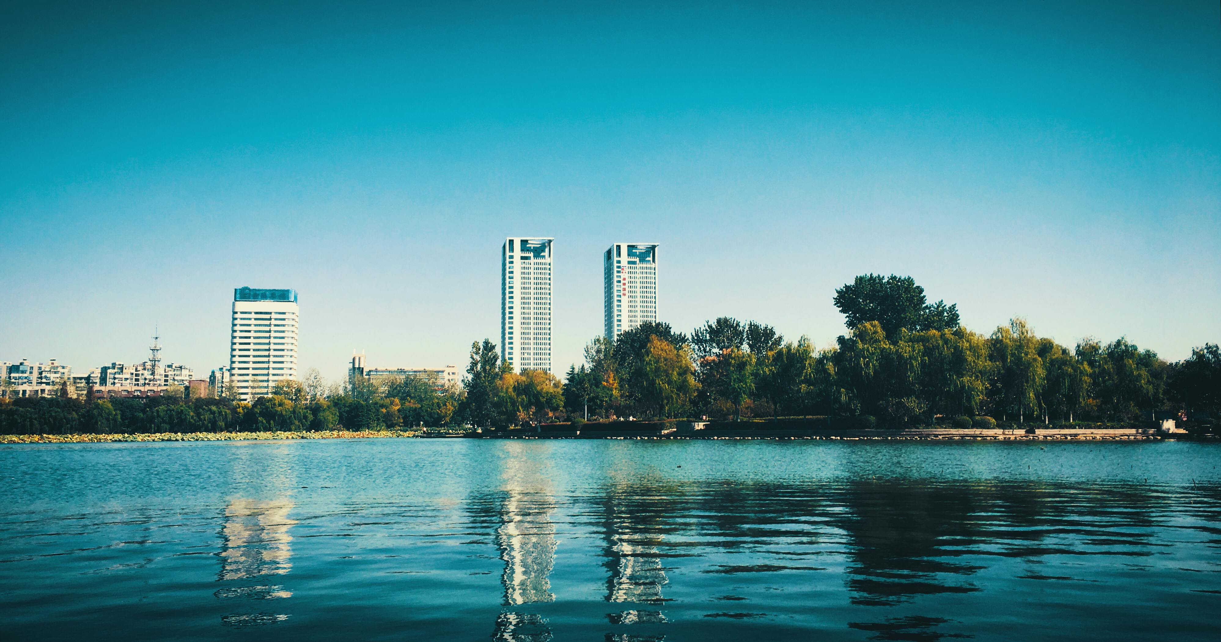 在晴朗的夏日天空下，平静的湖泊映衬着南京宁静的城市天际线