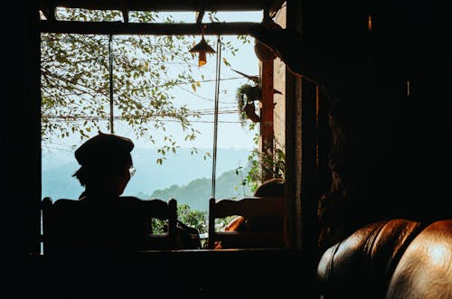 Silhouette of Person Sitting on Chair Facing Window