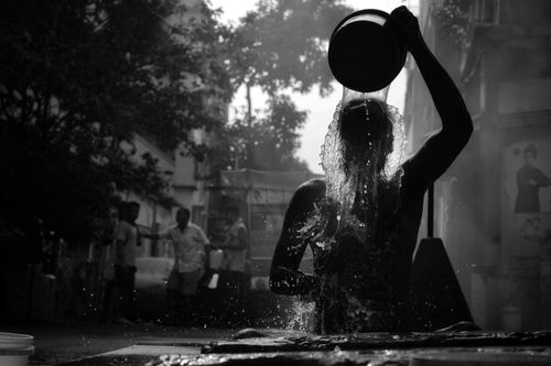 Free A striking silhouette of a man pouring water from a pot outdoors in Kolkata, India. Stock Photo