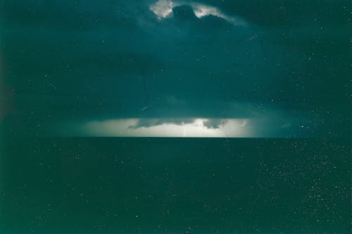 A dark green photo of a storm over the ocean