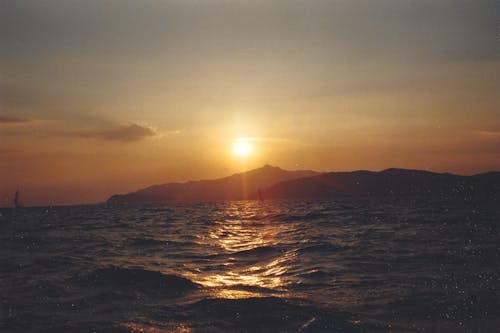 A sunset over the ocean with mountains in the background