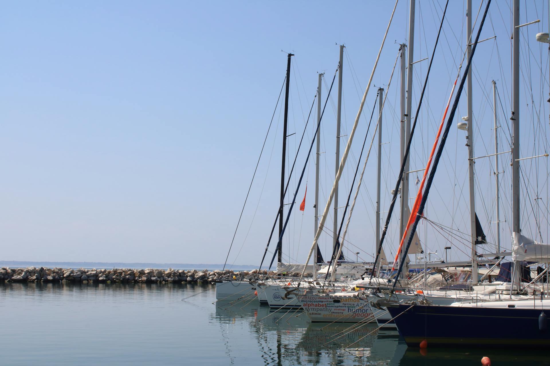Serene view of sailboats moored at Thessaloniki harbor with clear blue sky.