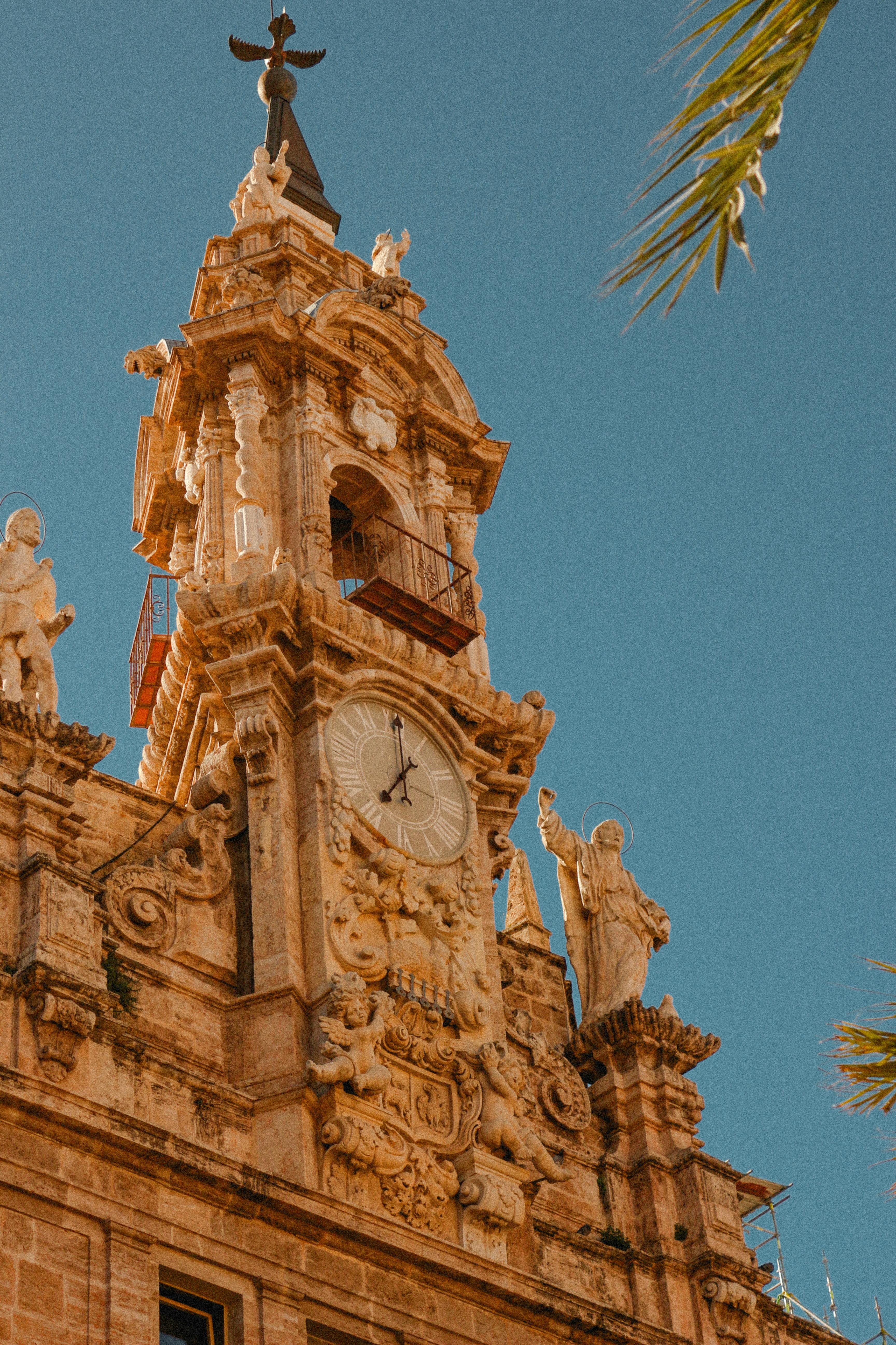 Majestic view of the ornate bell tower in Valencia, showcasing intricate architecture details against a clear blue sky.