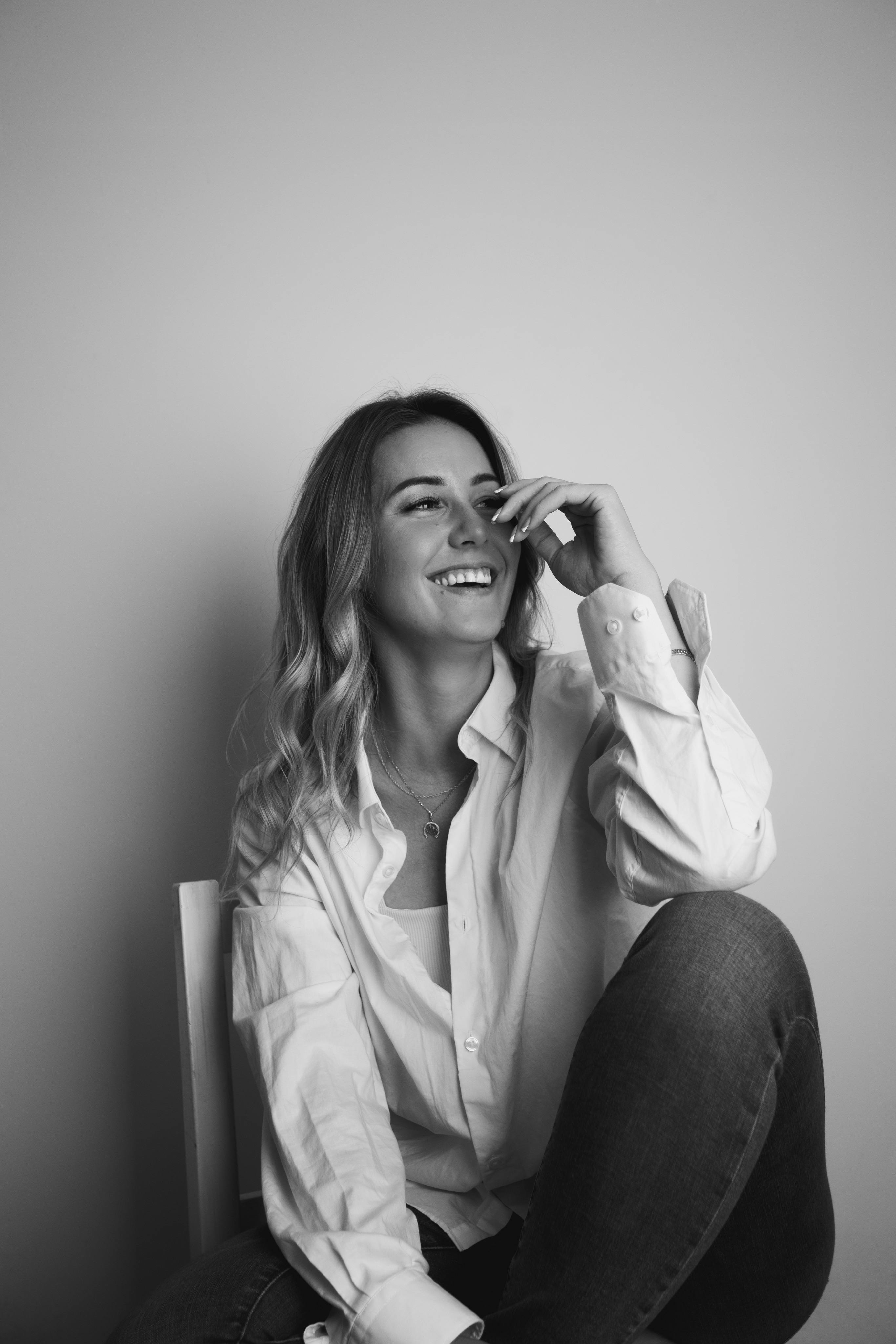 Elegant black and white portrait of a smiling woman in a studio setting.