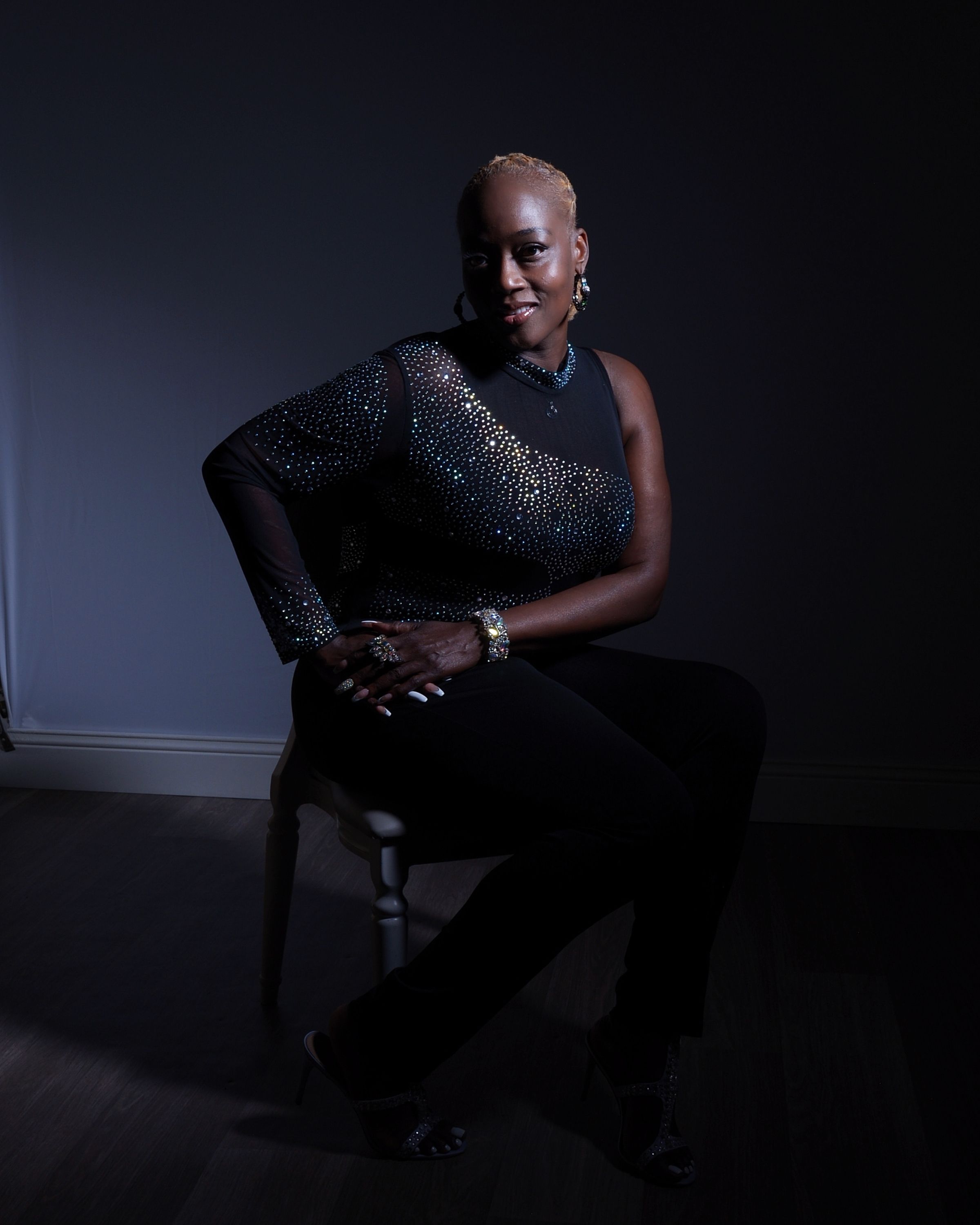 A woman sitting on a chair in a dark room · Free Stock Photo
