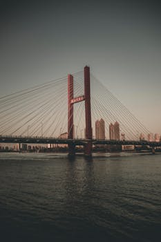 日落时分，悬索桥横跨城市河流，可欣赏天际线景色