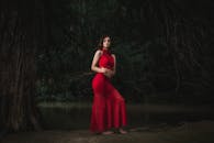 在宁静的森林中，一位身着红色连衣裙的女子优雅地摆着姿势
