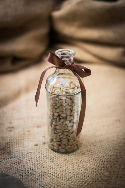 Coffee Beans in Clear Glass Bottle on Brown Textile