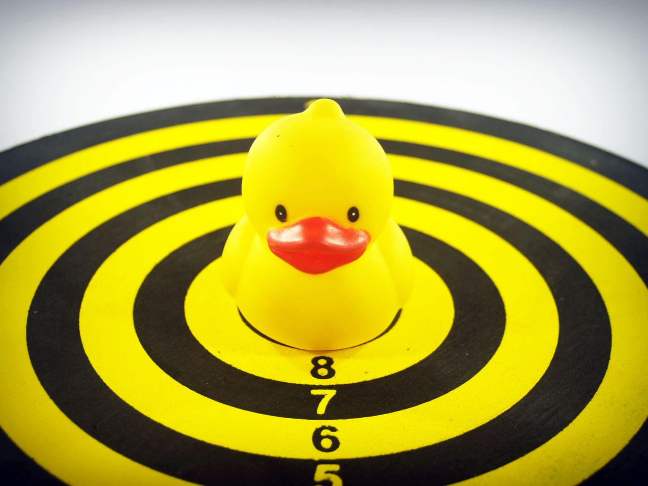 a playful rubber duck sits on a dartboard highlighting fun and precisi
