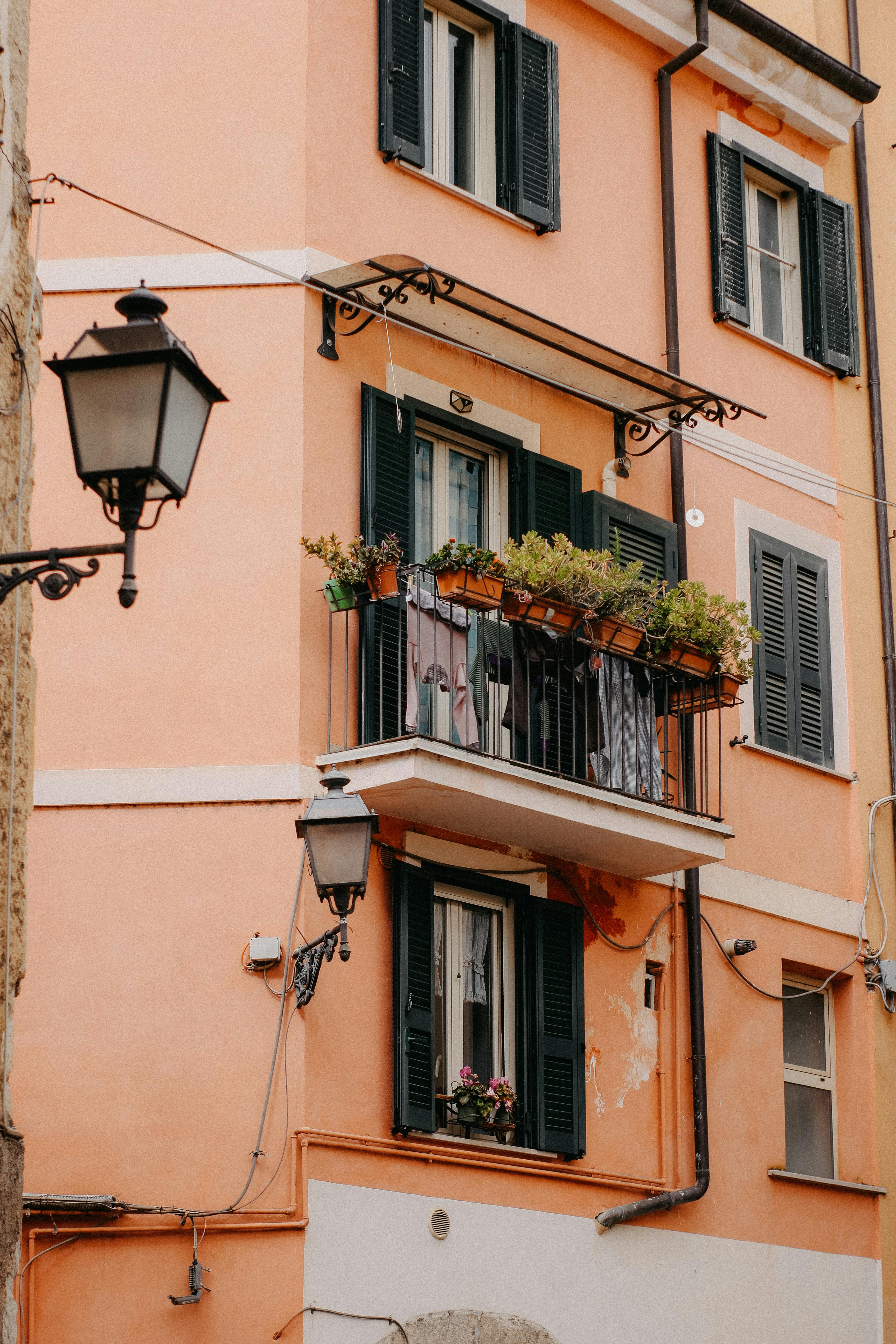 Charming old town facade with balconies, shutters, and potted plants.