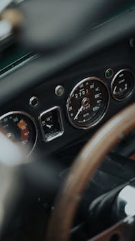Close-up view of a classic car dashboard featuring a vintage speedometer and steering wheel.