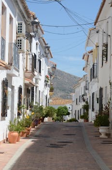Idyllic whitewashed facades line a narrow street in Frigiliana, Spain, epitomizing Mediterranean charm.
