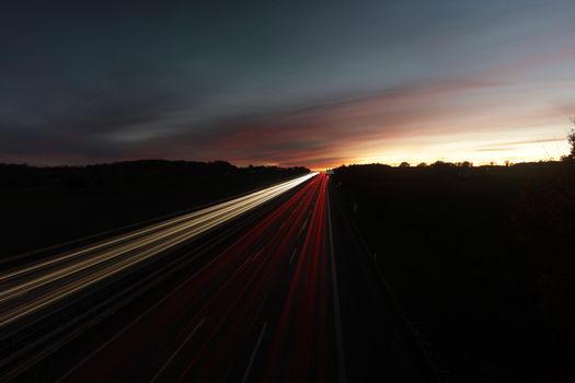 Long exposure of highway tail lights at dusk in Germany's countryside.