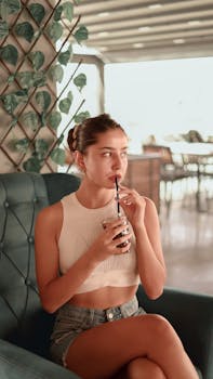 Young woman enjoying a refreshing drink indoors at a chic İstanbul café. Relaxed and stylish atmosphere.