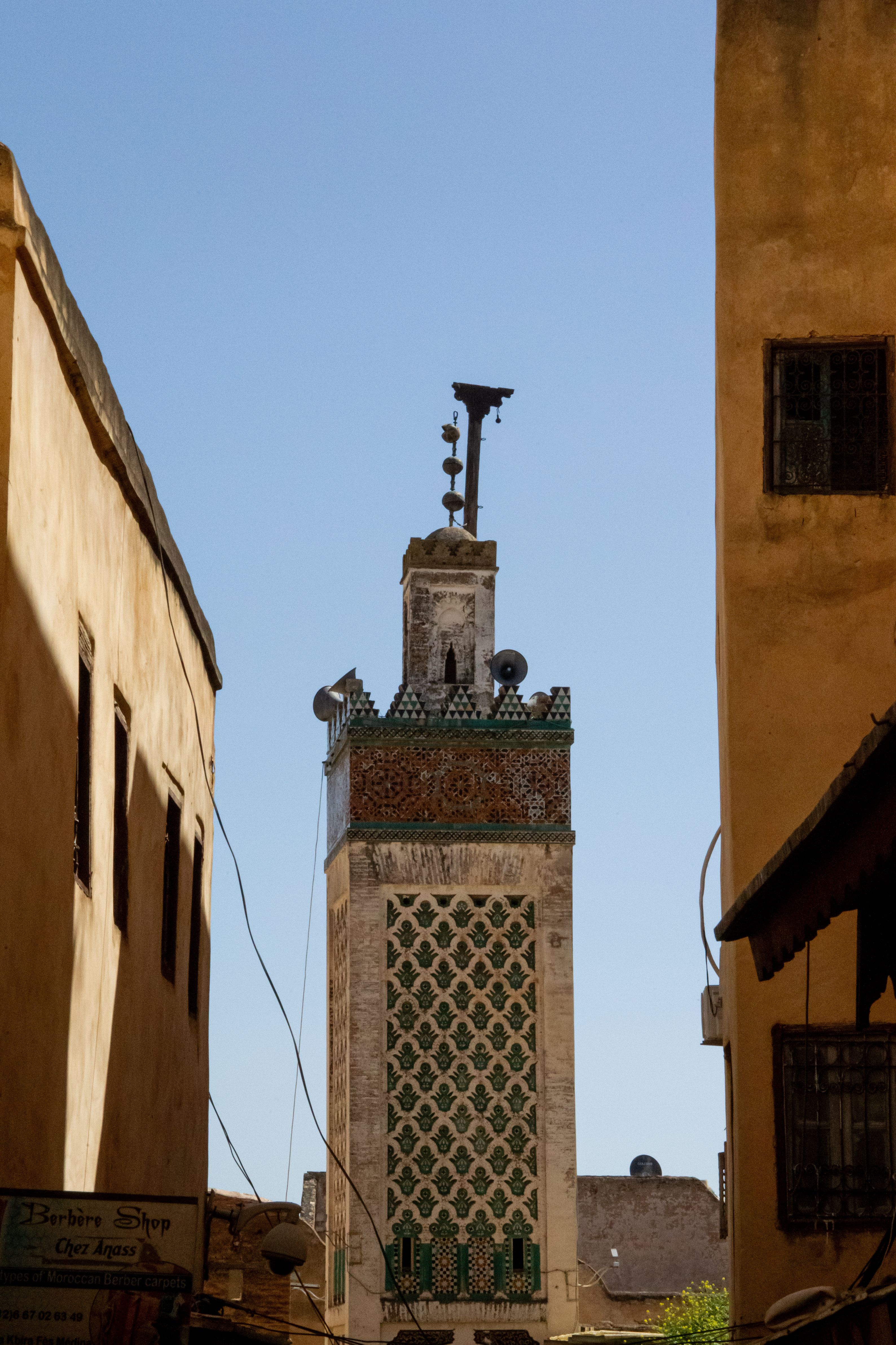 Beautiful view of a traditional mosque minaret in Fes, Morocco under clear blue skies.
