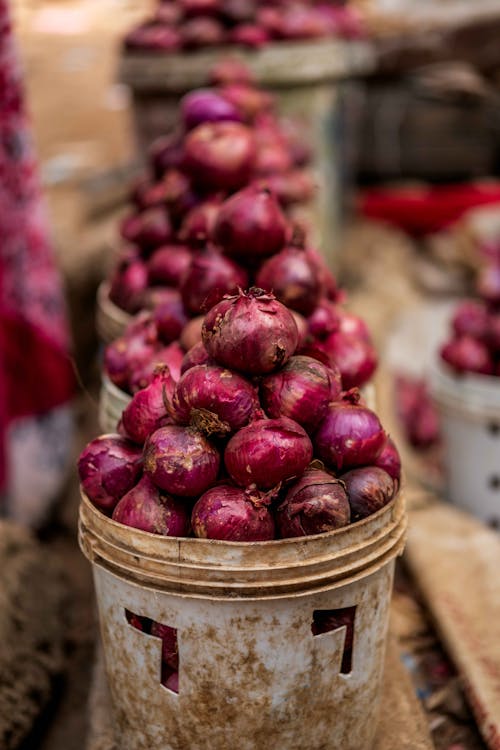 A pile of onions in buckets on a table