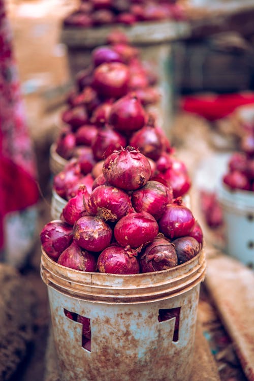 A pile of onions in buckets on a table
