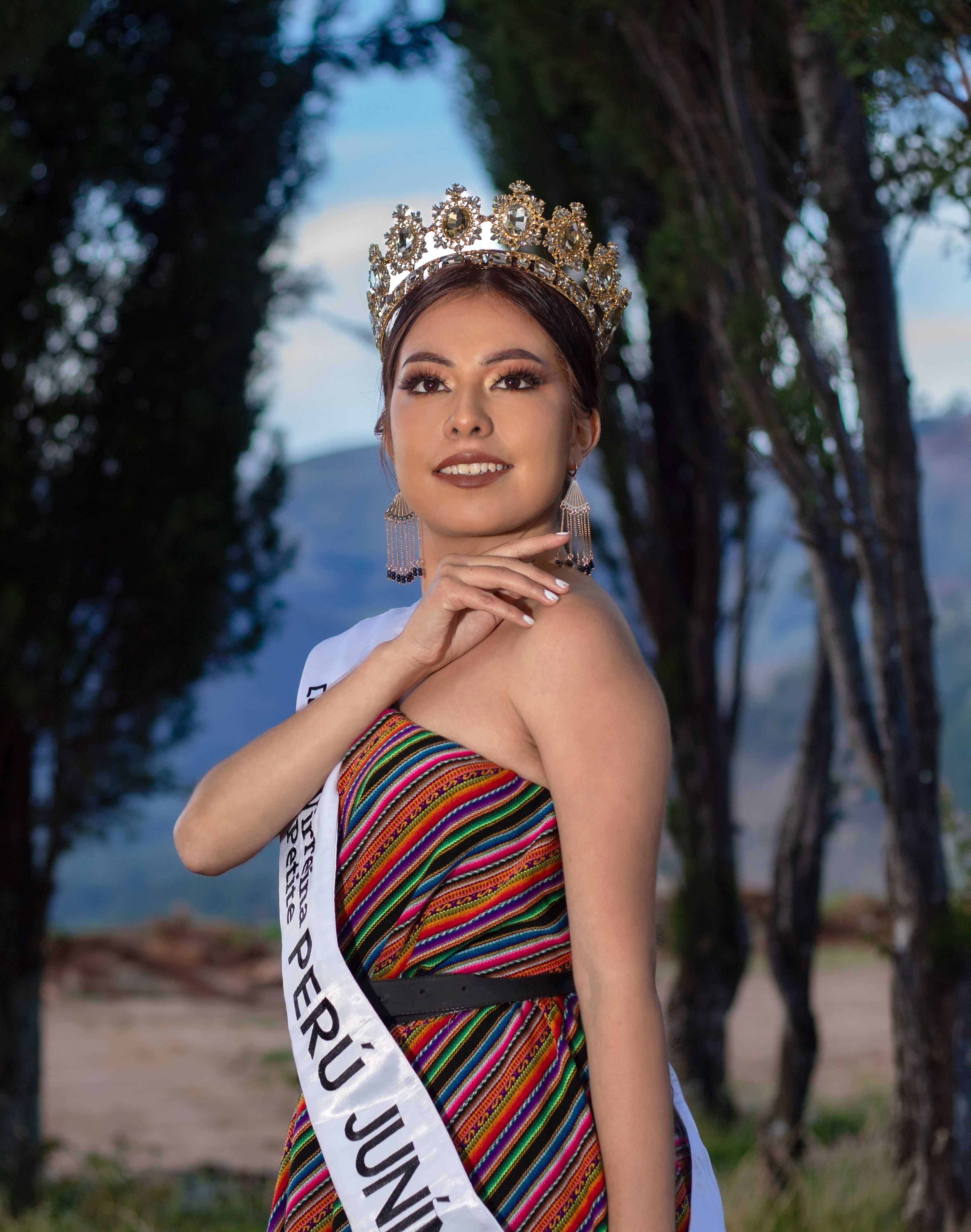 Portrait of a Peruvian beauty queen wearing a dazzling crown and traditional dress in Junín, Peru outdoors.