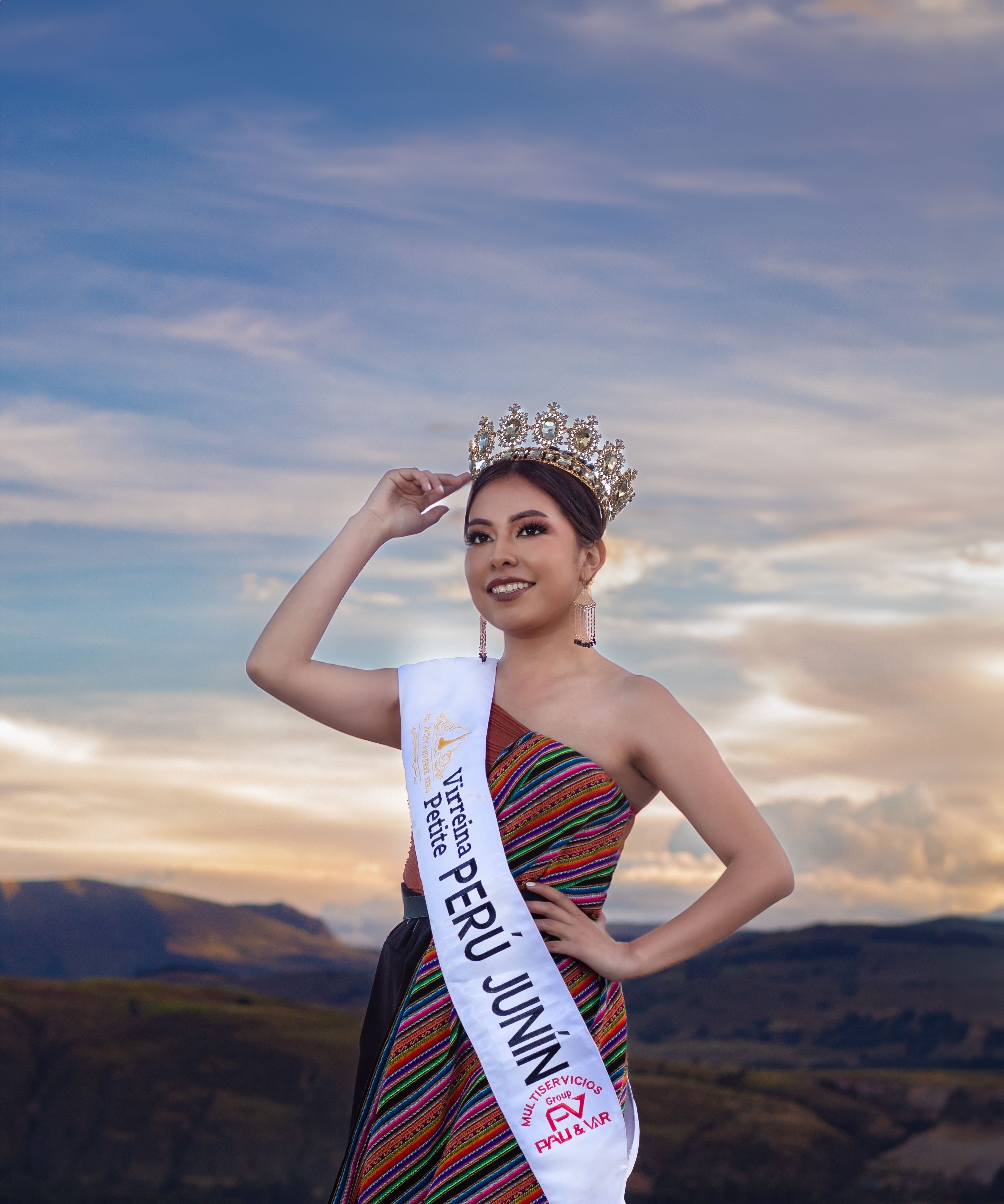 A Peruvian beauty queen wearing a crown poses against a scenic sunset in Junín, Perú.
