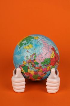 Vibrant photo of hands holding a globe against an orange backdrop. 22669707