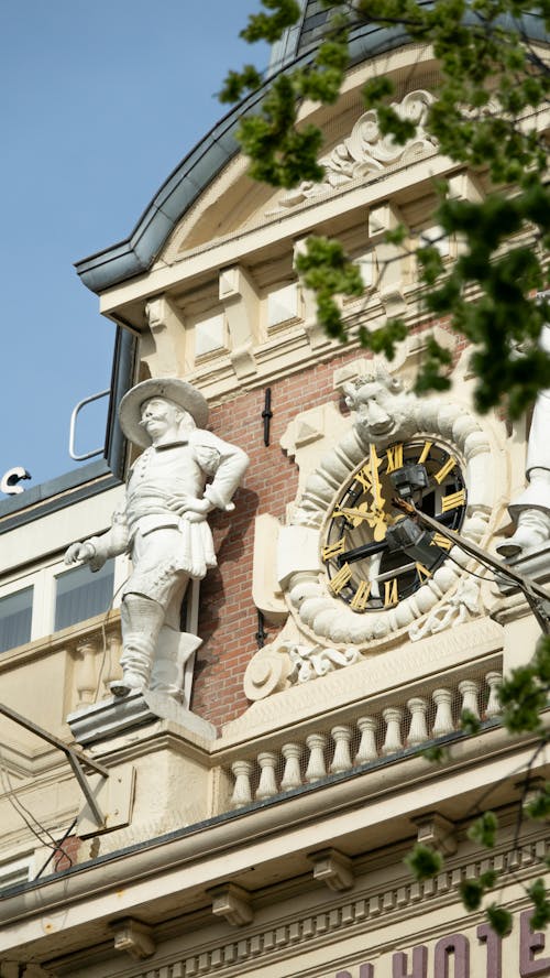 A clock on the side of a building with statues