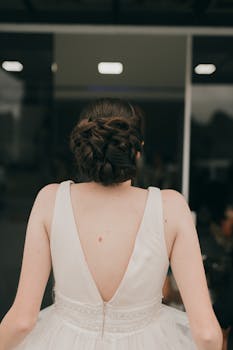 A stunning bride in a white wedding dress showcasing an elegant updo from behind.
