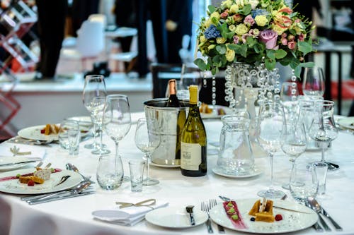 White Labeled Bottle Near Clear Glass Wine Bottle on White Round Table