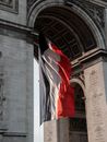 Low angle flag of France waving under Arc de Triomphe in Paris on sunny day
