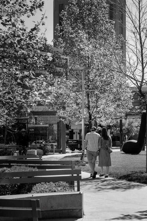 A black and white photo of a couple walking in a park