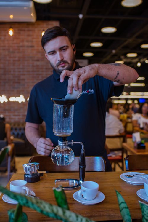 Free Barista using a siphon brewer in a cozy café setting. Stock Photo
