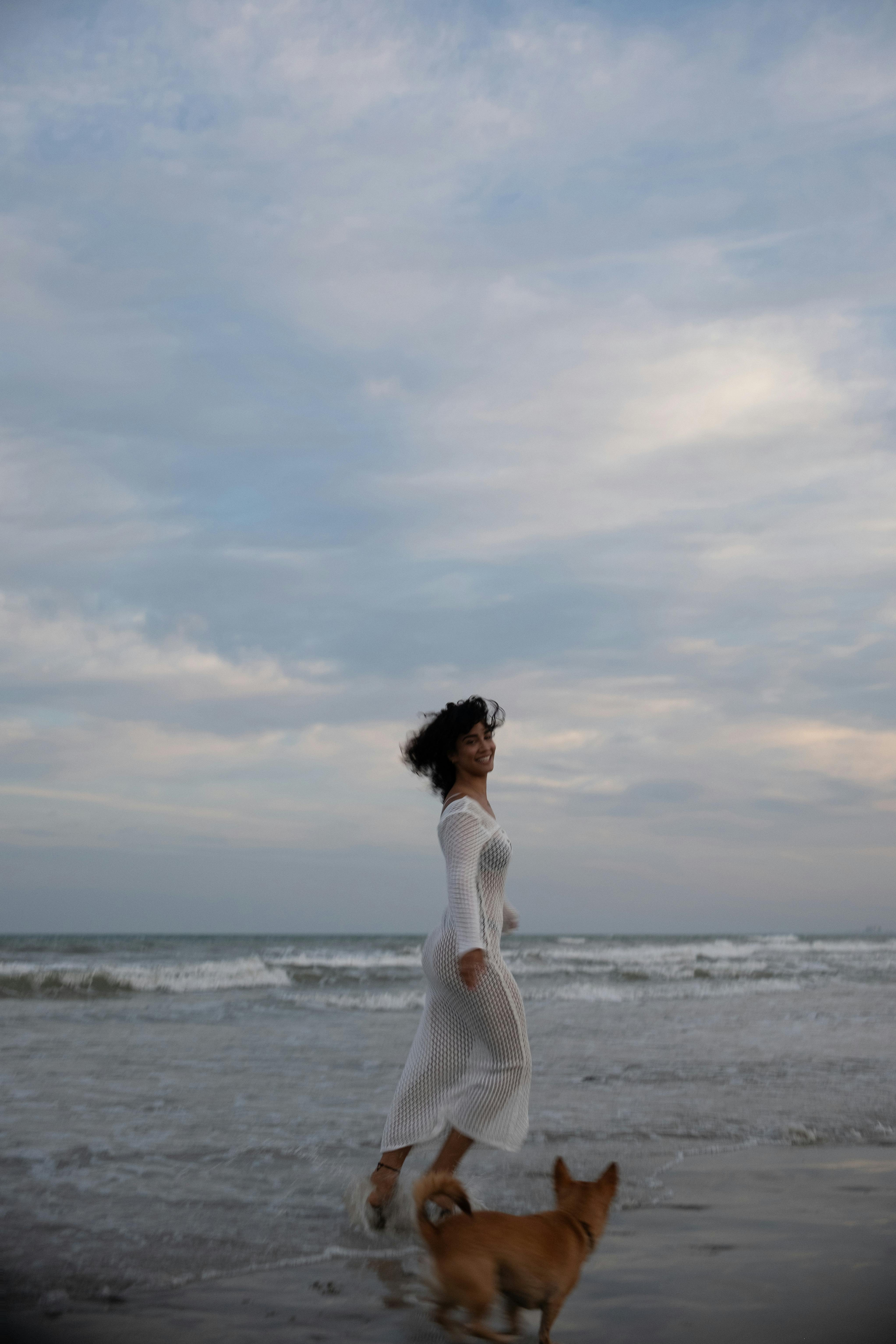 woman running with dog on beach in sea