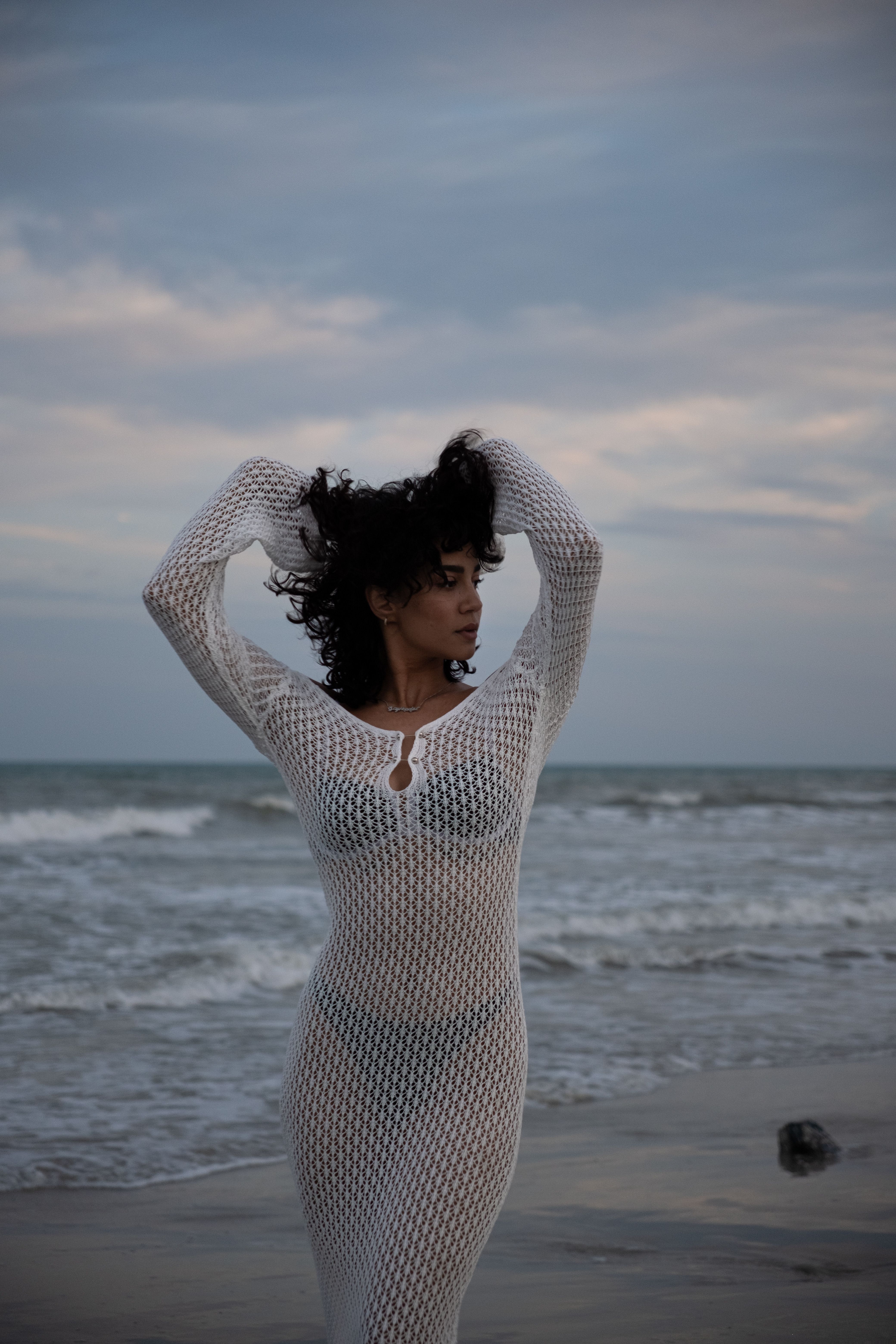 Young Woman in a White Dress Posing on a Beach with her Hands in Hair ...