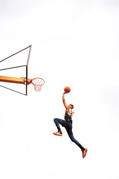 A man performing an impressive basketball dunk outdoors against a clear sky.