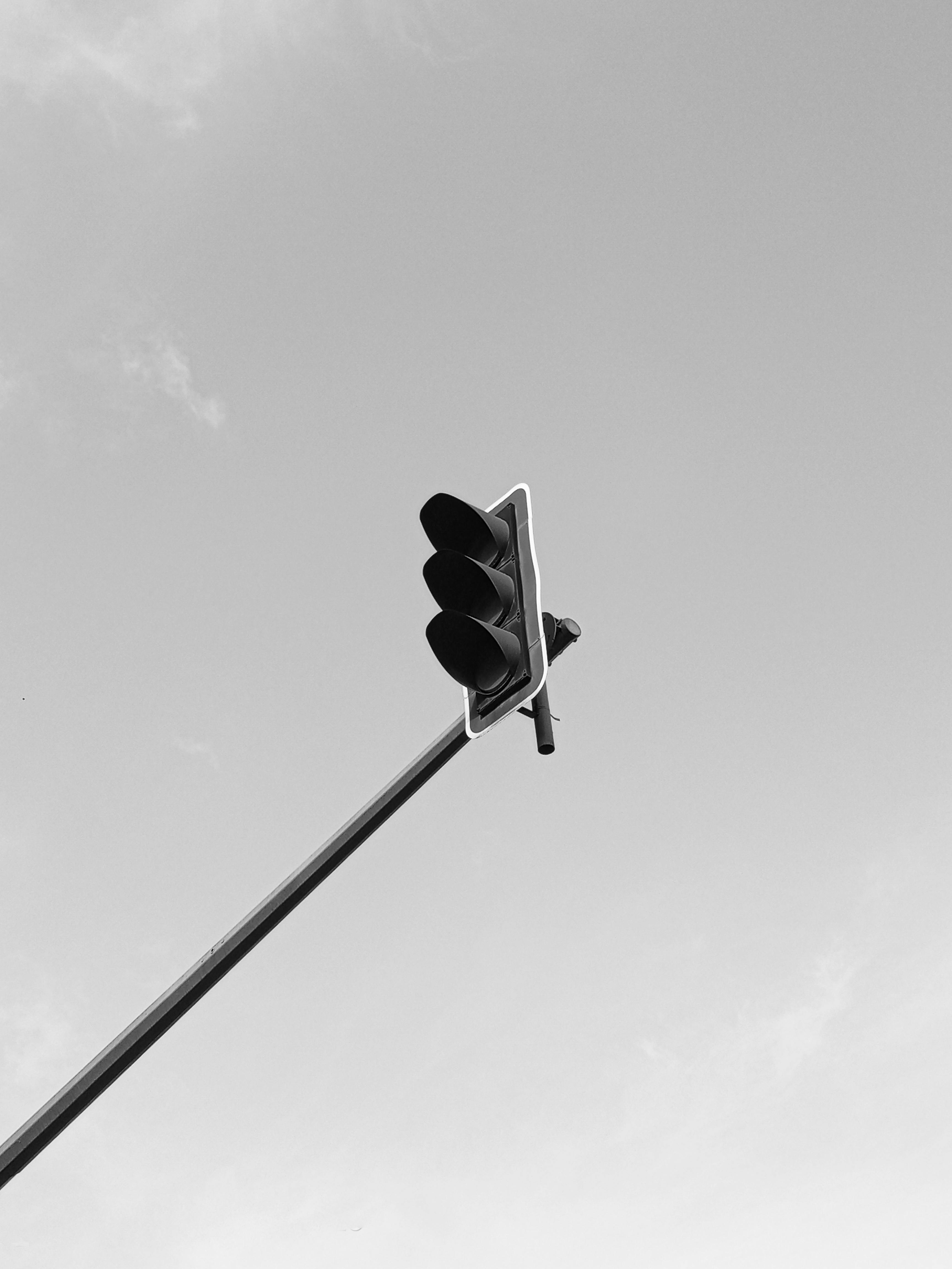 Minimalist black and white photo of a traffic light against a clear sky.