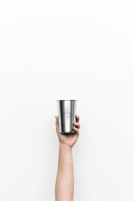 A minimalist photo of a hand holding a metal cup against a plain white background.