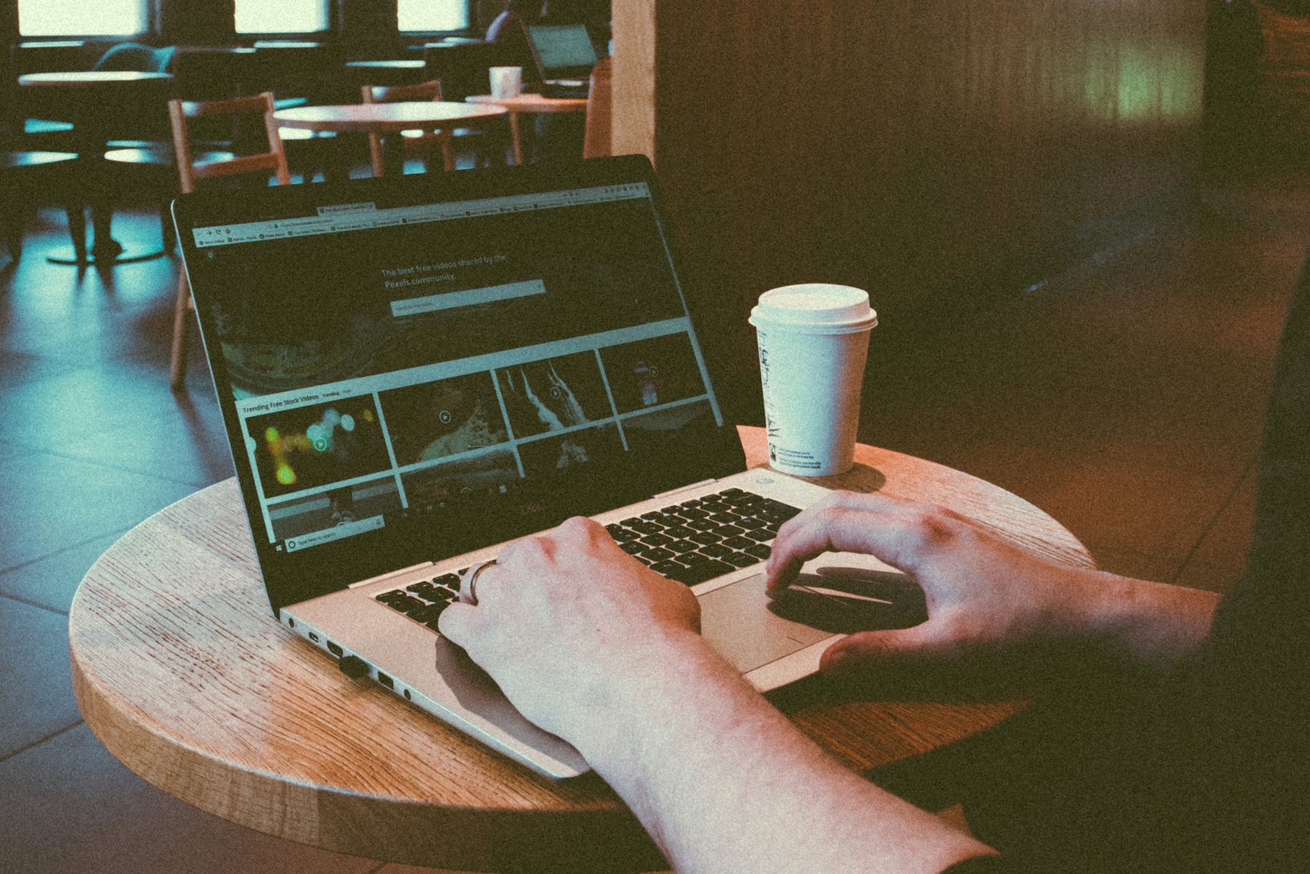 personne tapant sur le clavier d'un ordinateur portable avec une tasse de café fumante