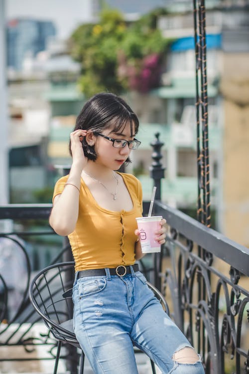 Free Woman Sitting on Chair Holding Disposable Cup Stock Photo