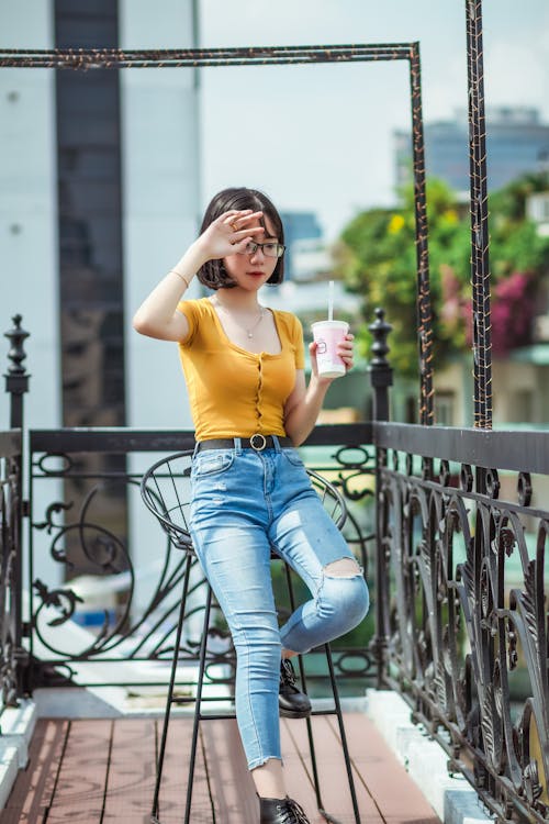 Photo De Mise Au Point Peu Profonde De Femme En T Shirt Jaune Tenant Une Tasse En Plastique Assis Sur Une Chaise De Bar