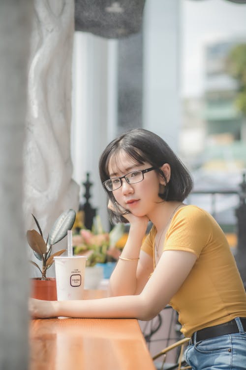 Free Woman Resting Head on Right Hand Leaning O Table Stock Photo