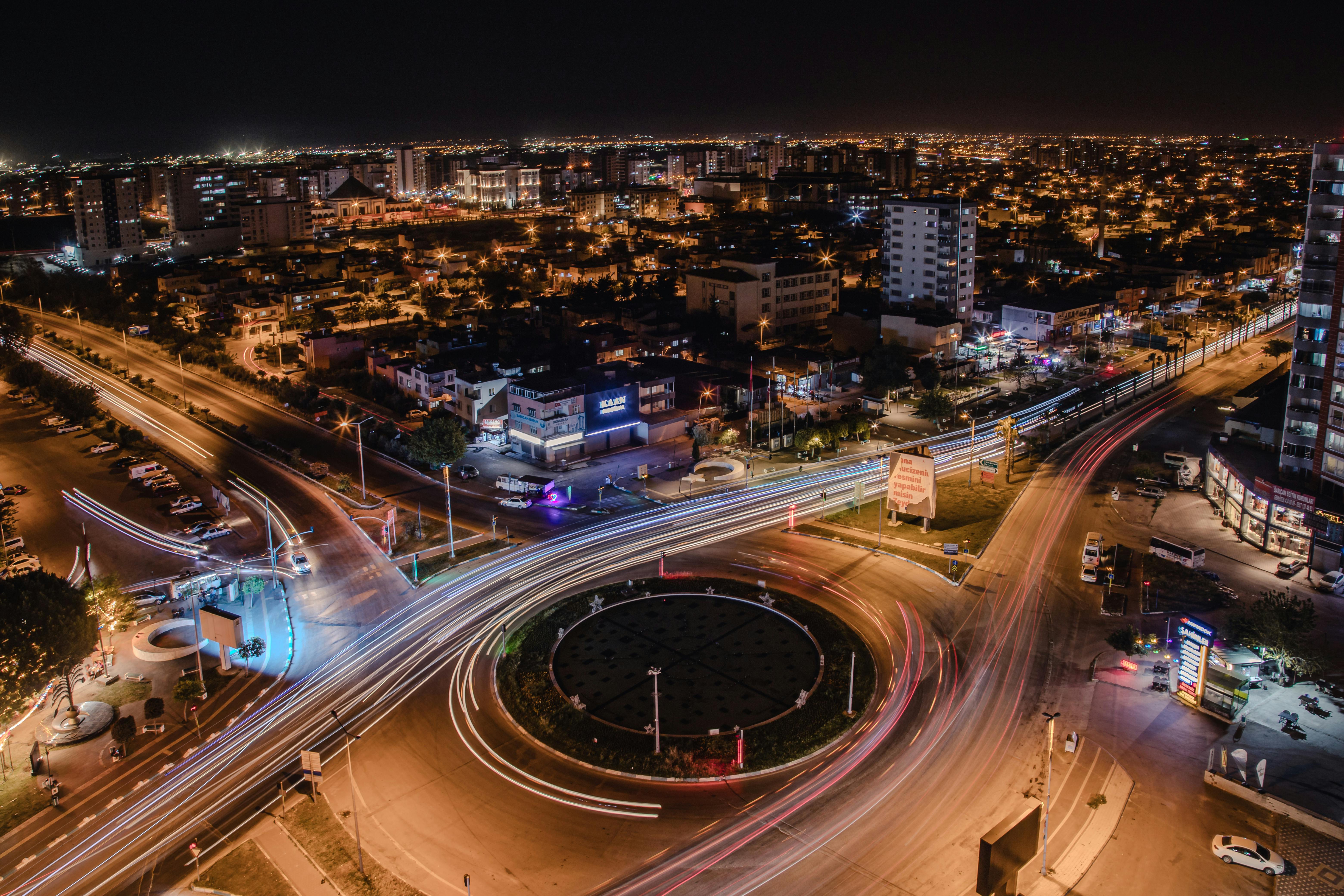 A vibrant aerial view of Adana at night, showcasing the bustling traffic and city lights.