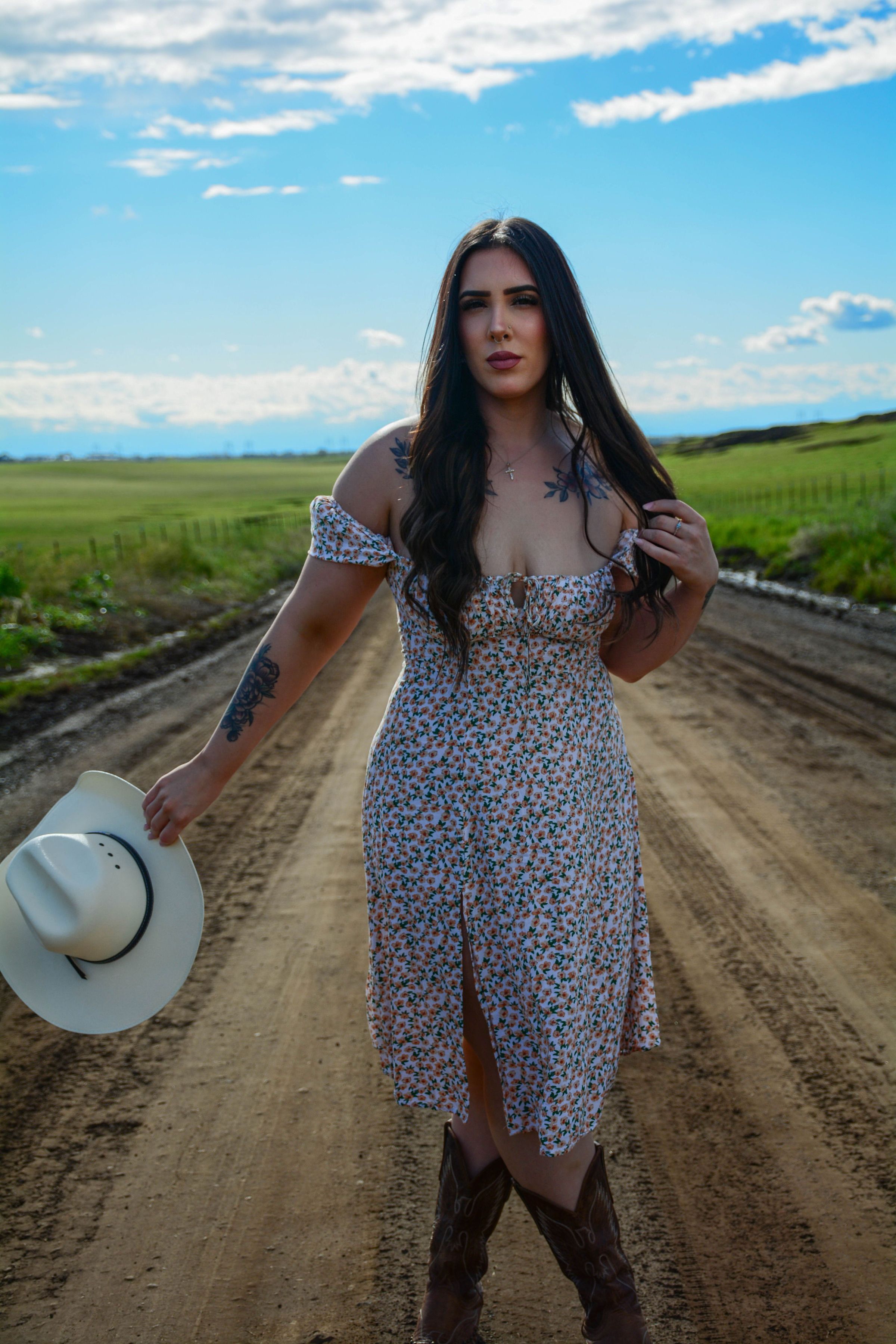 woman in dark floral midi dress with brown cowboy boots