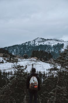 冬日里，一个徒步旅行者背着背包站在那里，俯瞰雪山景观