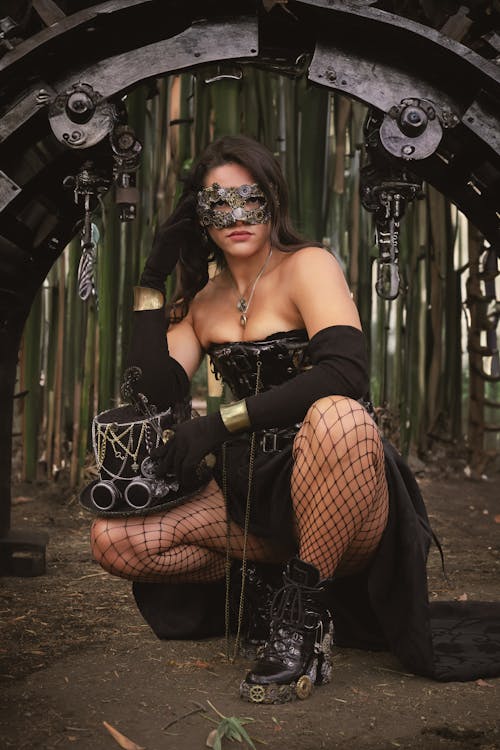 A woman in a steampunk costume posing in front of a large metal wheel