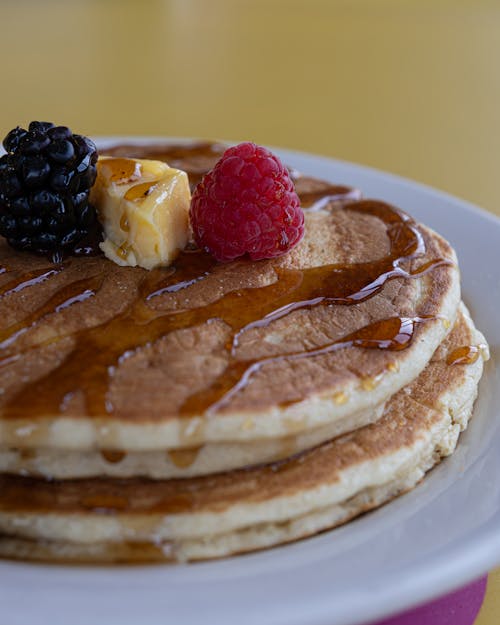 A stack of pancakes topped with syrup and berries